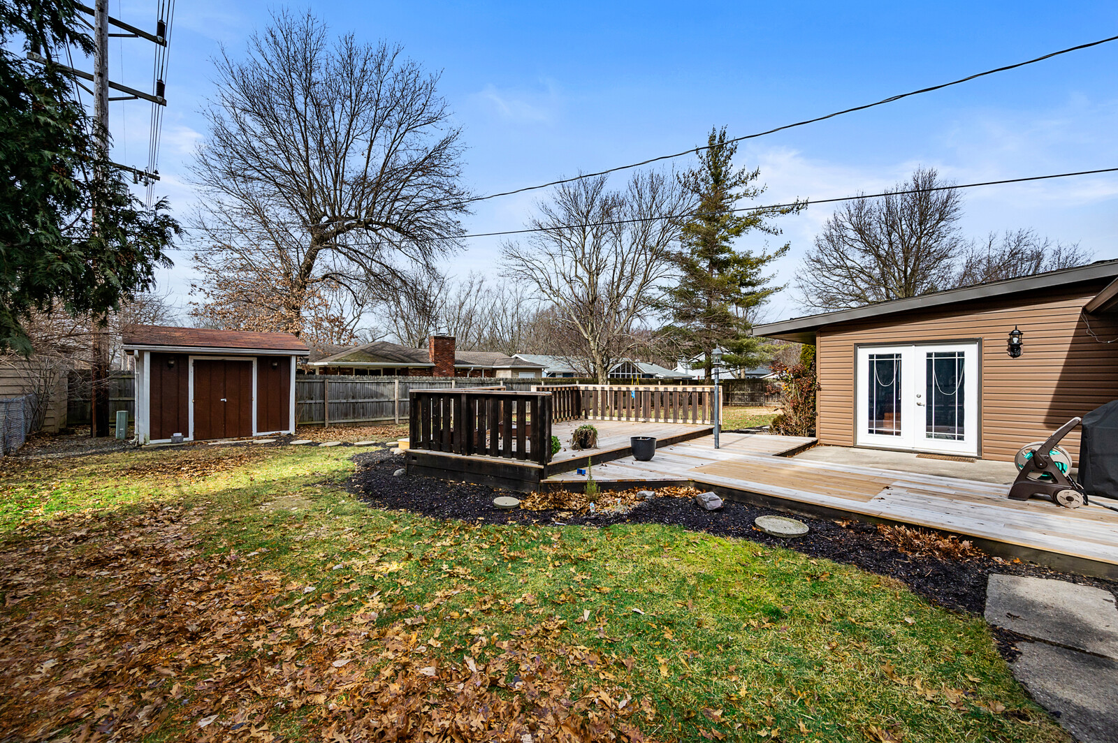 Residential backyard with deck, detached structures and surrounding property